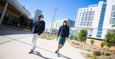 Two UC San Diego students wearing facial masks stroll through the North Torrey Pines Living and Learning Neighborhood